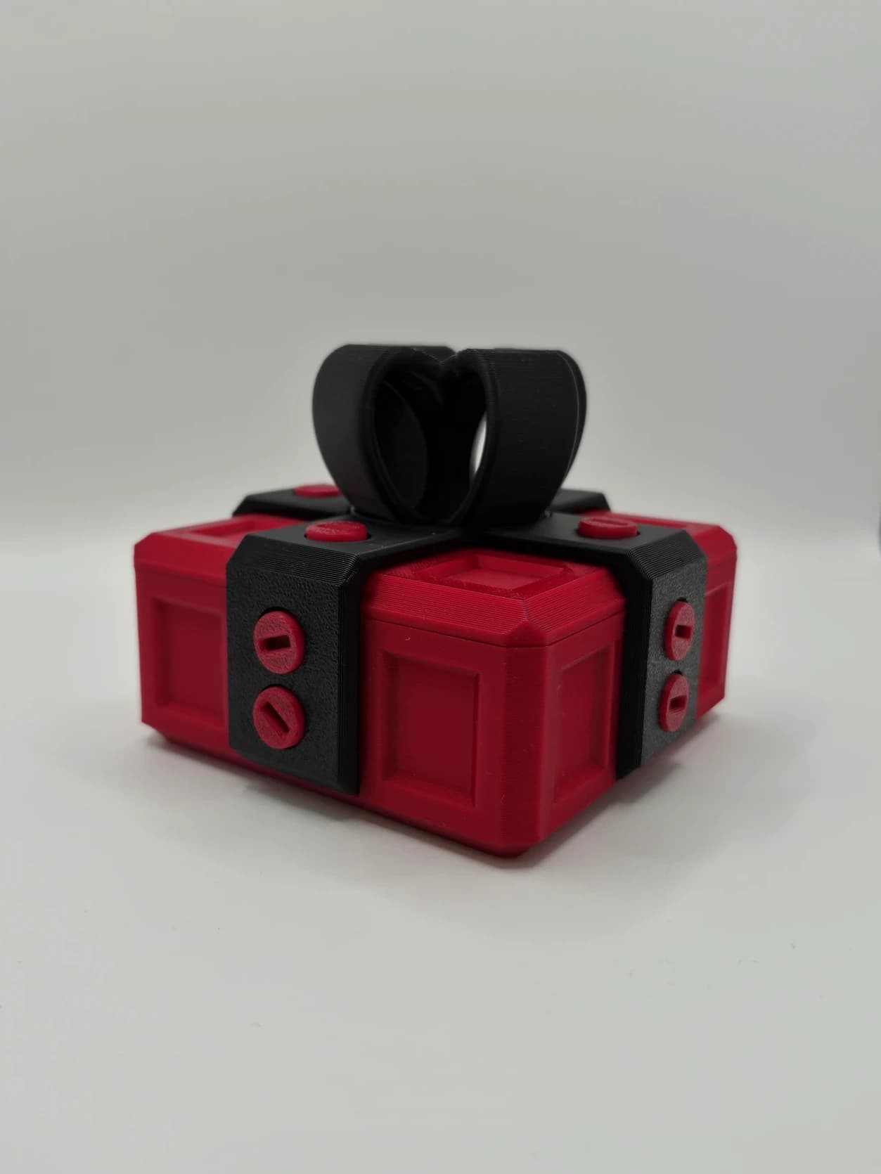Małe czerwone pudełko na prezent z czarną kokardą – łamigłówka 3D